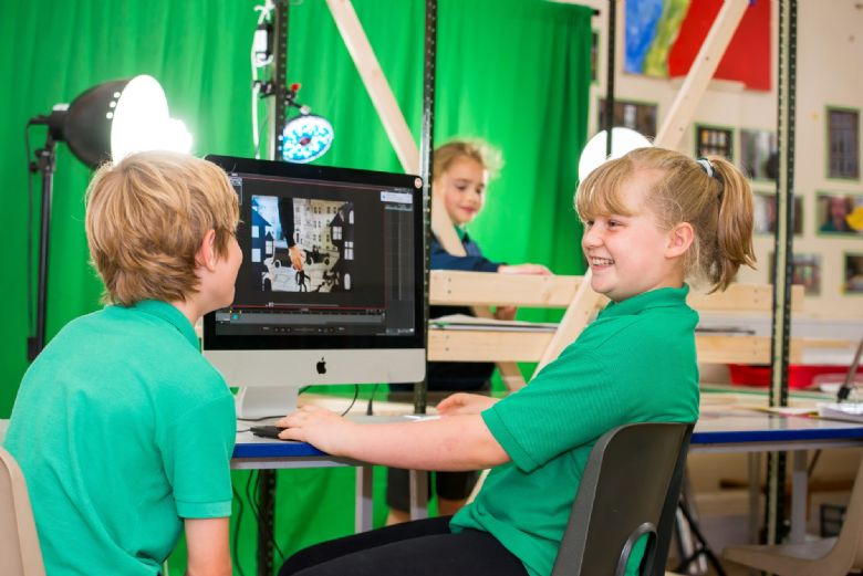 two pupils sitting in front of an iMac in a media class